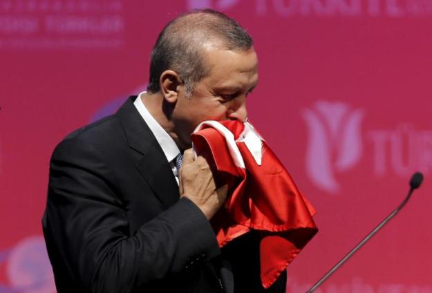 FILE PHOTO: Turkey's President Erdogan kisses a handmade Turkish flag, given him as a gift from Ugandan university student Cemil, during a graduation ceremony in Ankara, Turkey